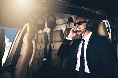 Buy stock photo Shot of a mature businessman using a headset while traveling in a helicopter