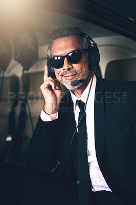 Buy stock photo Portrait of a mature businessman using a headset while traveling in a helicopter