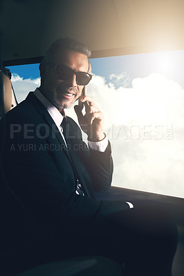 Buy stock photo Shot of a mature businessman using a mobile phone while traveling in a helicopter