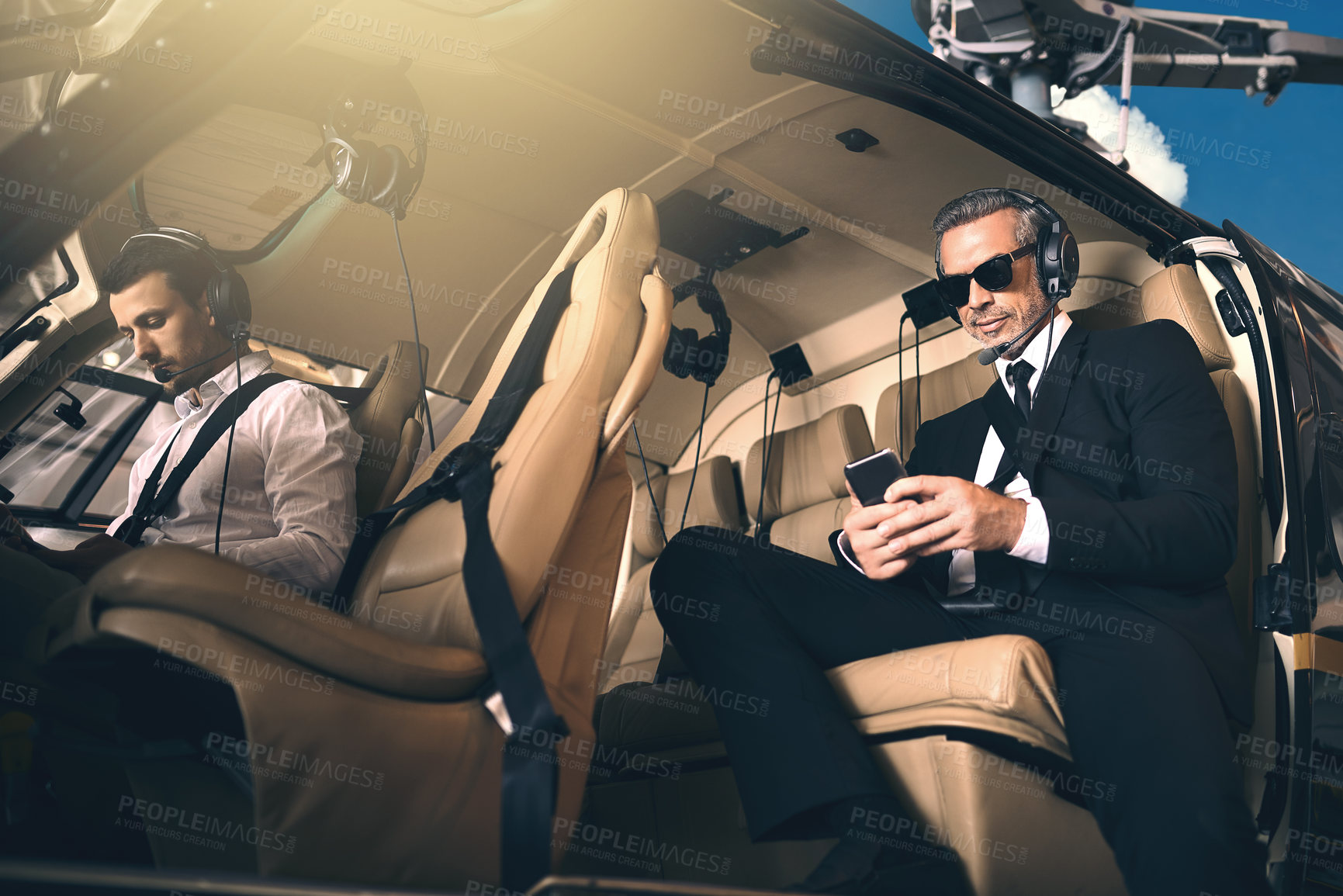 Buy stock photo Shot of a mature businessman using a mobile phone while traveling in a helicopter
