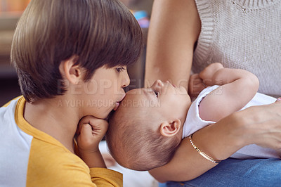 Buy stock photo Shot of an adorable little boy kissing his baby brother while his mother cradles him at home