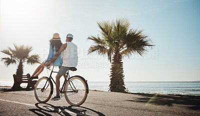 Buy stock photo Shot of a young couple riding a bicycle together on the promenade