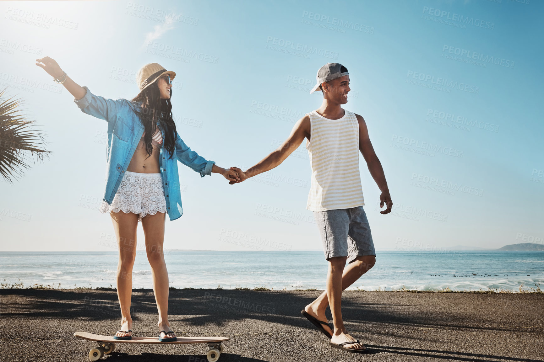 Buy stock photo Shot of a young man teaching his girlfriend how to skateboard on the promenade