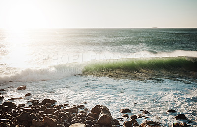 Buy stock photo Shot of water crashing against some boulders at the beach