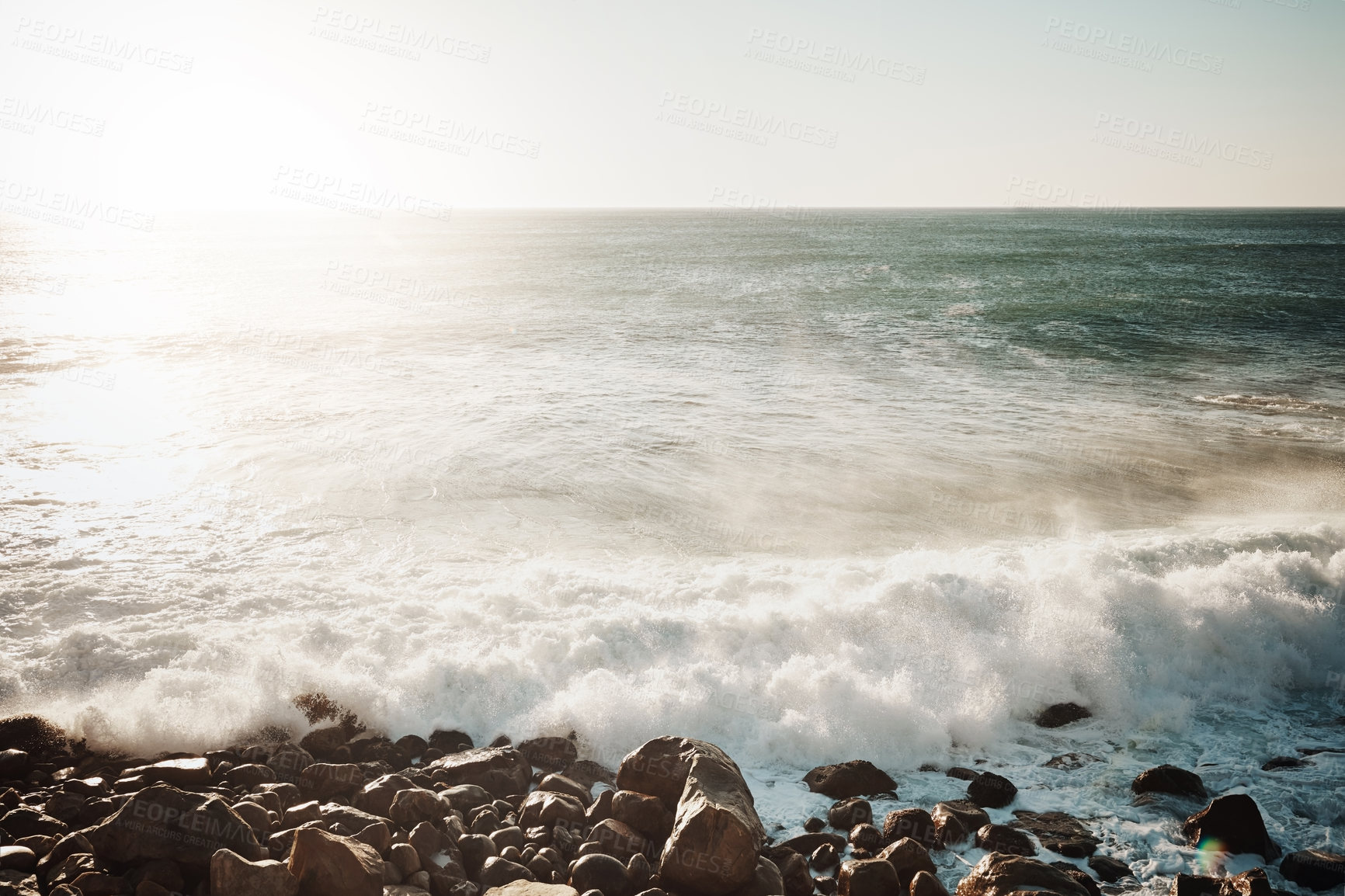 Buy stock photo Shot of water crashing against some boulders at the beach