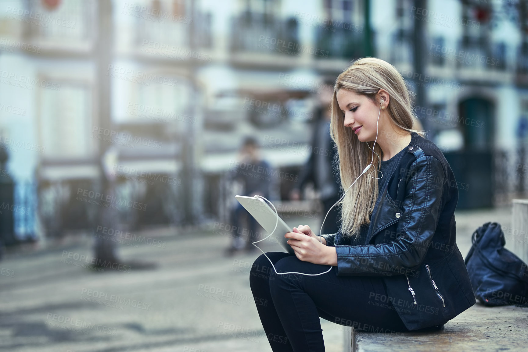 Buy stock photo Shot of an attractive woman using a digital tablet and earphones in the city
