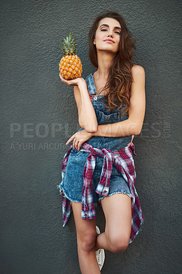 Buy stock photo Portrait of a cheerful young woman holding a pineapple while standing against a grey background
