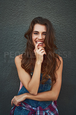Buy stock photo Portrait of a cheerful young woman posing against a grey background outside during the day