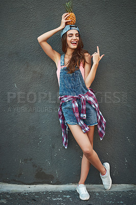 Buy stock photo Shot of a cheerful young woman holding a pineapple on her head while standing against a grey background