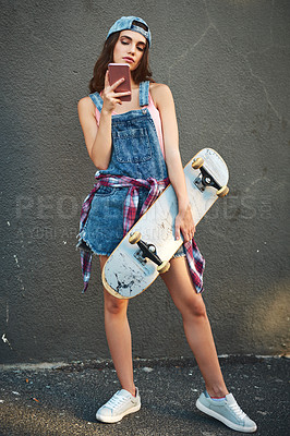 Buy stock photo Portrait of a carefree young woman holding a skateboard while standing against a grey background