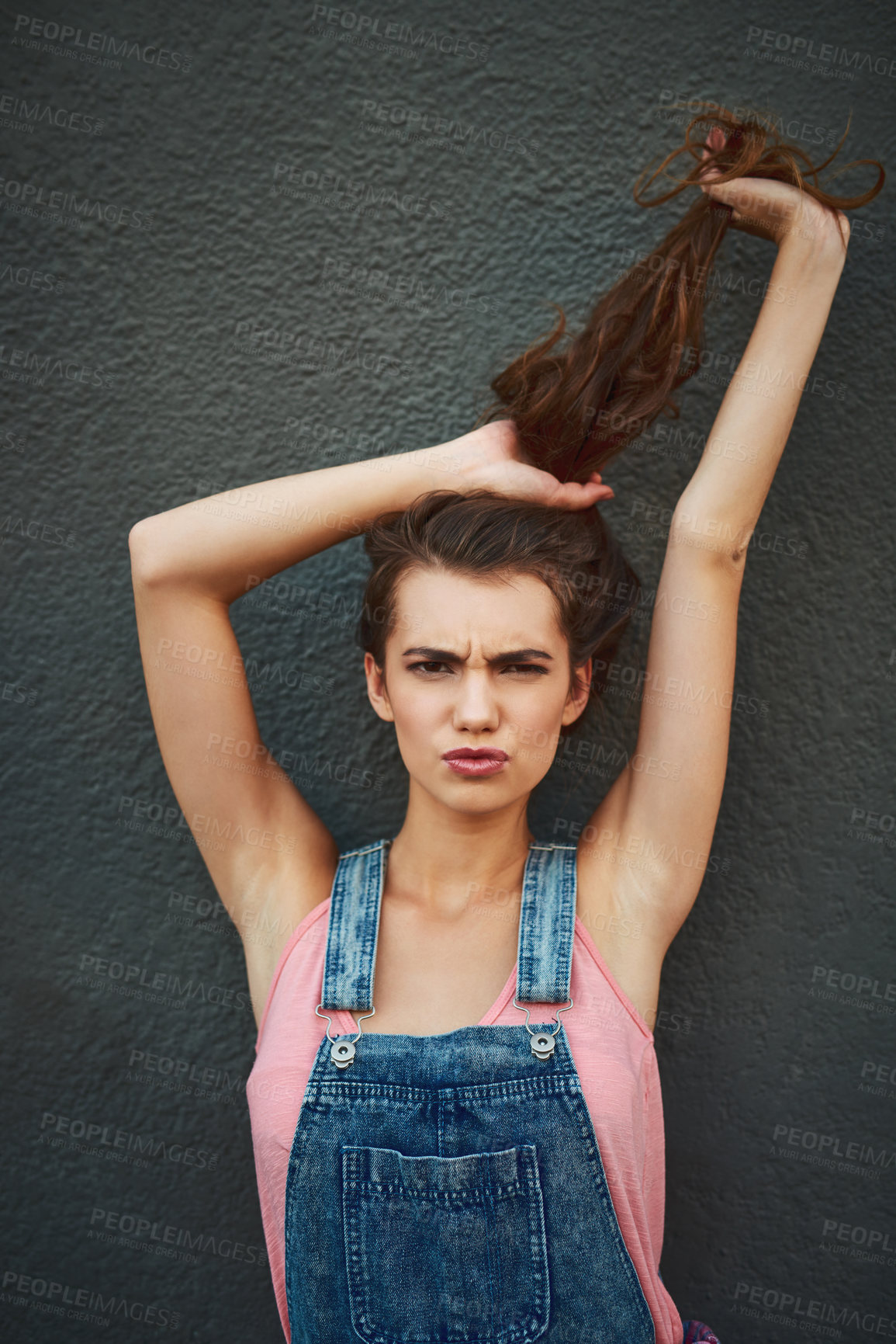 Buy stock photo Portrait of a carefree young woman holding her hair up while standing against a grey background