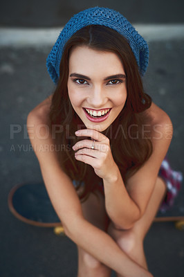 Buy stock photo Portrait of a cheerful young woman seated on a skateboard outside during the day