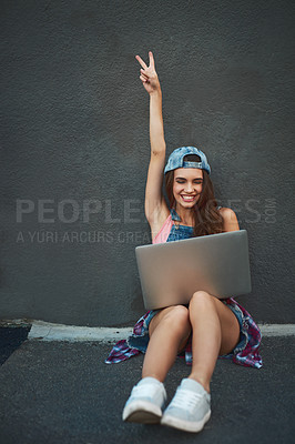 Buy stock photo Shot of a cheerful young woman working on a laptop while raising her hand and being seated against a grey background