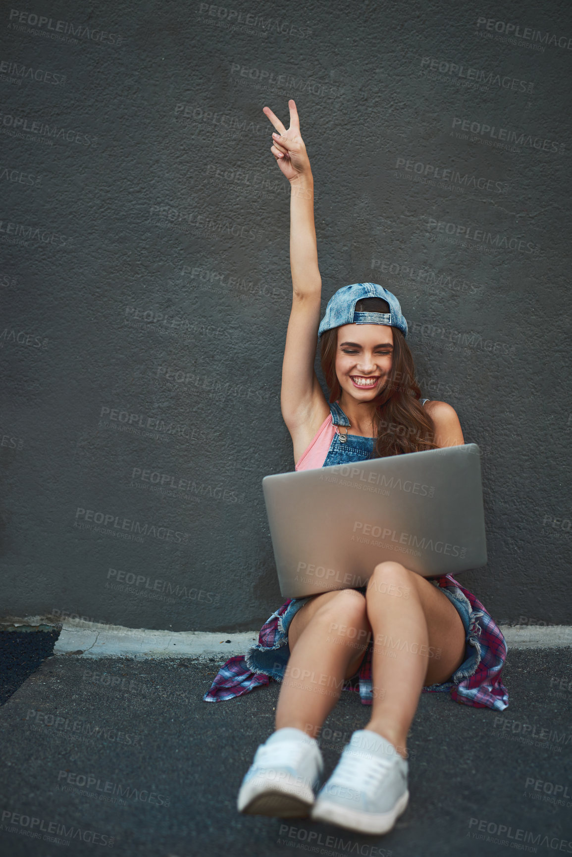 Buy stock photo Shot of a cheerful young woman working on a laptop while raising her hand and being seated against a grey background