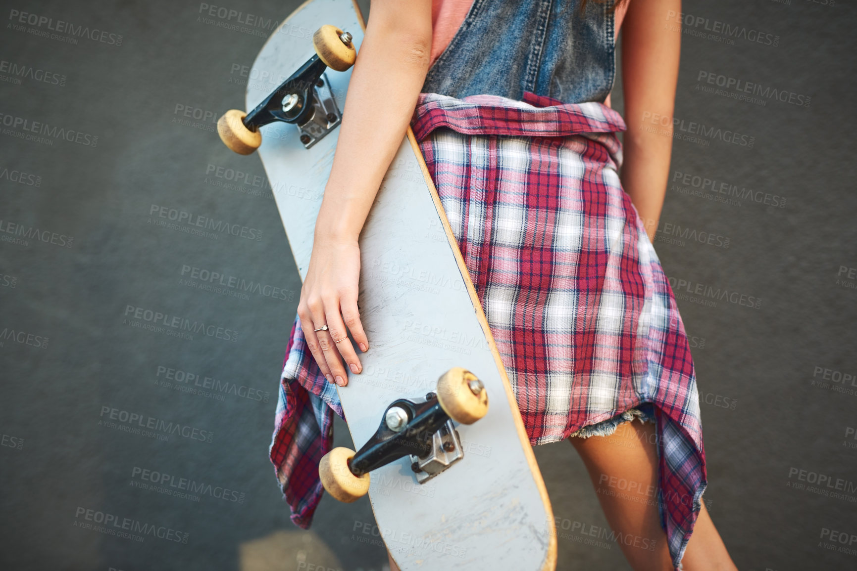 Buy stock photo Shot of an unrecognizable woman holding a skateboard while standing against a grey background