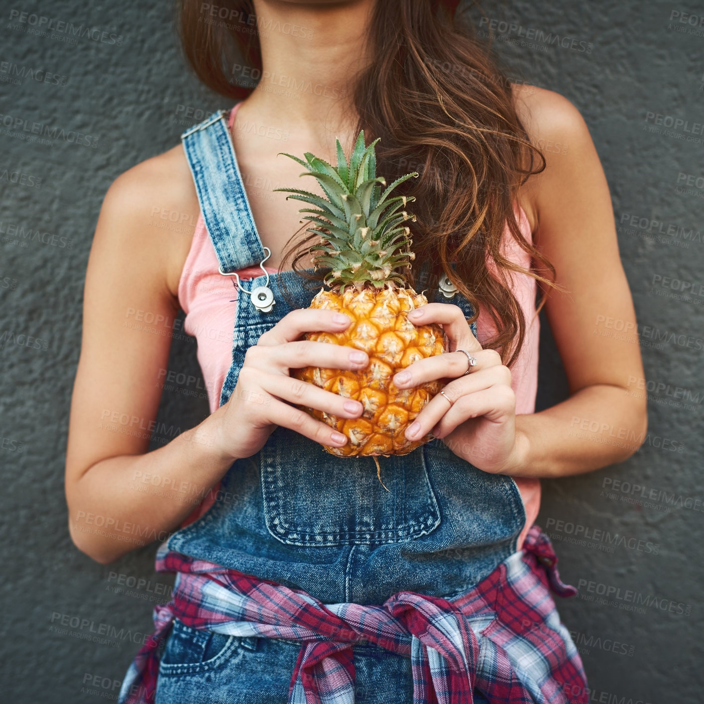 Buy stock photo Shot of an unrecognizable young woman holding a pineapple while standing against a grey background