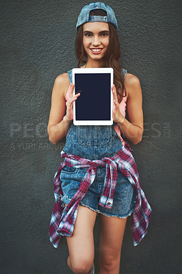 Buy stock photo Portrait of a cheerful young woman holding a digital tablet in front of her while standing against a grey background