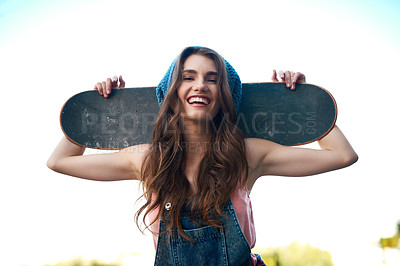 Buy stock photo Portrait of an attractive young female skater holding a skateboard behind her back outside during the day