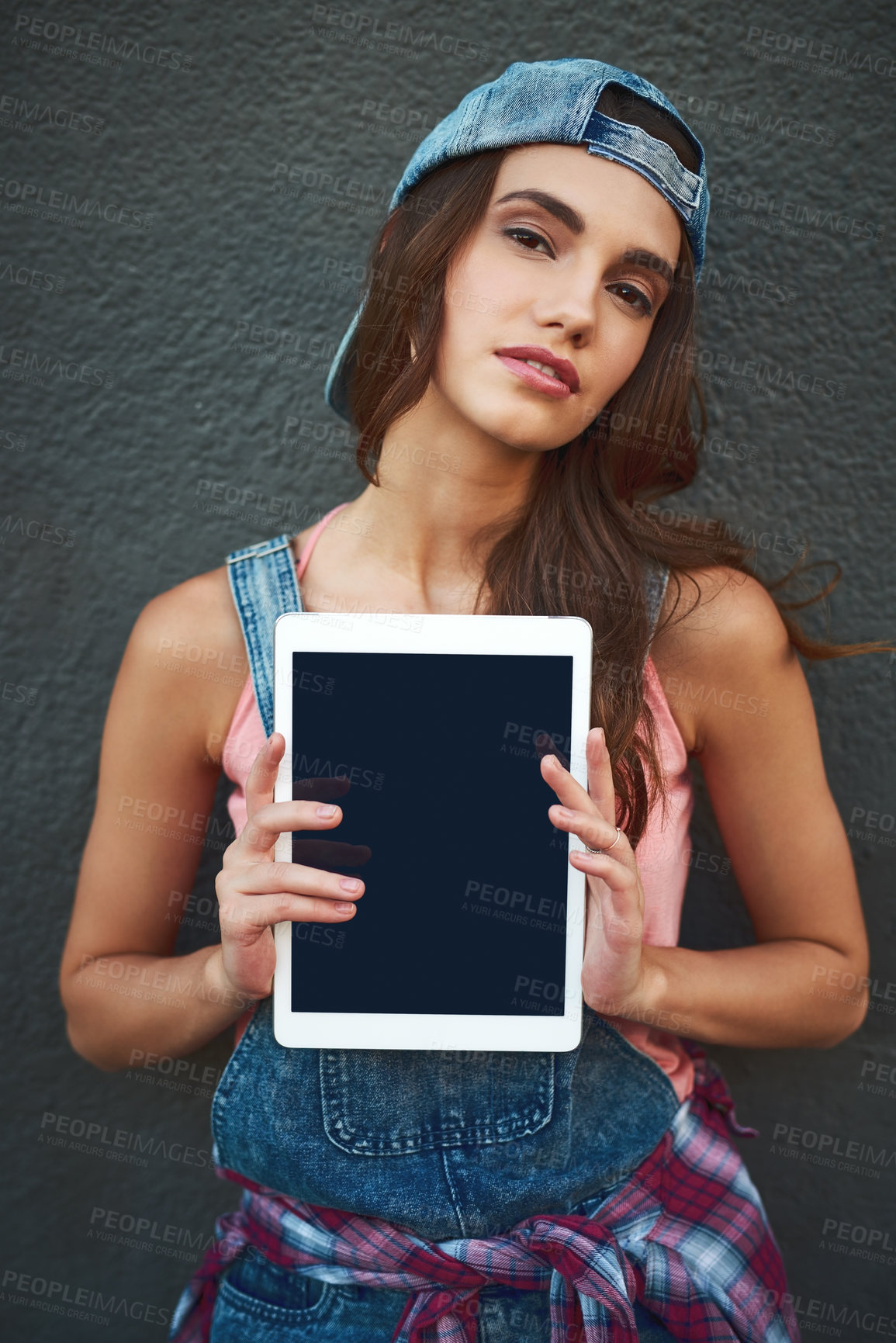 Buy stock photo Portrait of an attractive young woman holding a digital tablet in front of her while standing against a grey background