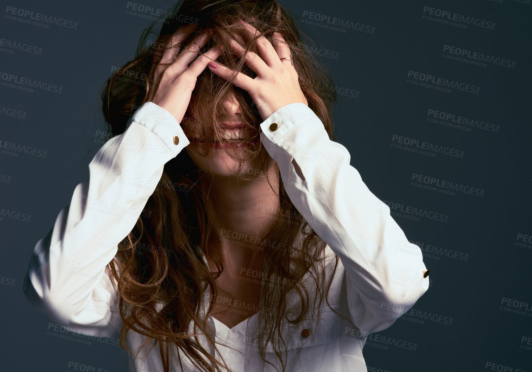 Buy stock photo Studio shot of an unrecognizable woman covering her face with her hair against a blue background