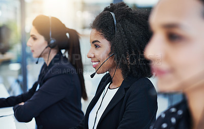 Buy stock photo Shot of a young woman working in a call center alongside her colleagues