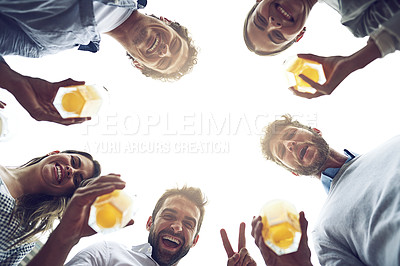 Buy stock photo Low angle portrait of a group of cheerful young work colleagues standing in a circle while drinking beer together outside during the day