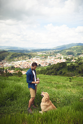 Buy stock photo Full length shot of a handsome young man taking his dog for a walk in the mountains