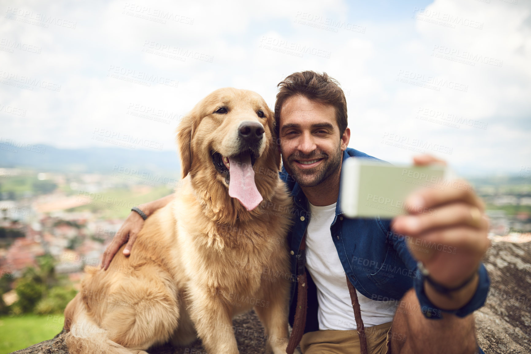 Buy stock photo Full length shot of a handsome young man and his dog taking selfies while resting during a hike in the mountains