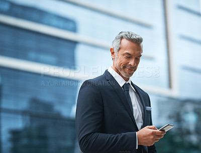 Buy stock photo Shot of a handsome mature businessman in corporate attire using a cellphone outside during the day