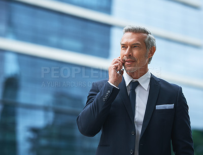 Buy stock photo Shot of a handsome mature businessman in corporate attire on a call outside during the day