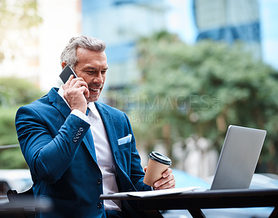 Buy stock photo Shot of a handsome mature businessman in corporate attire on a call and using a laptop outside during the day