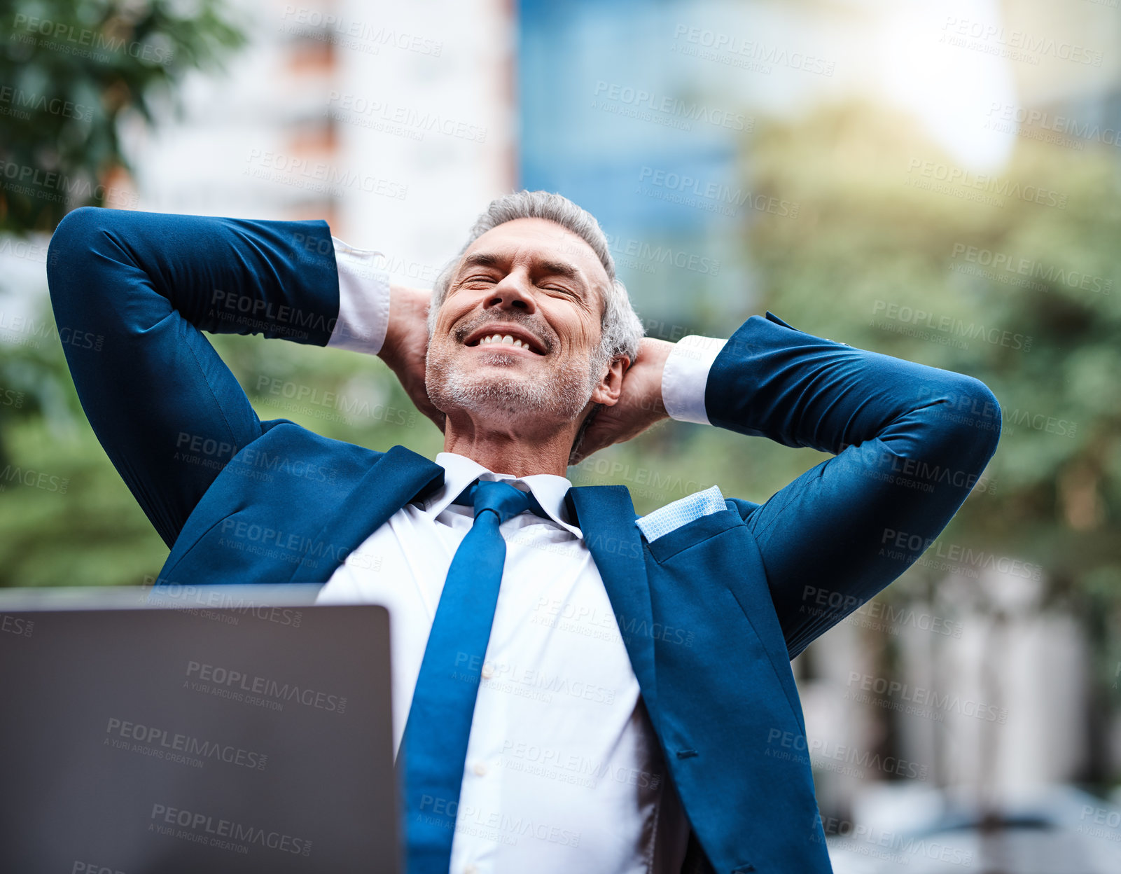 Buy stock photo Shot of a cheerful mature businessman with his hands behind his head relaxing outside during the day