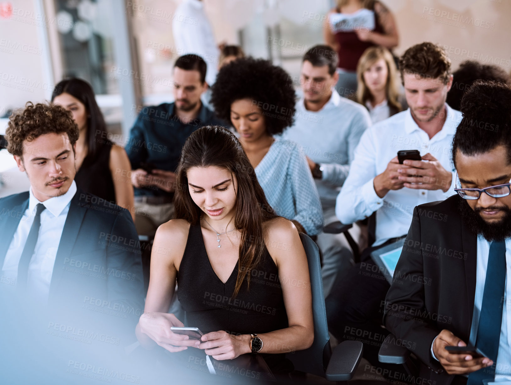 Buy stock photo Shot of a group of businesspeople using their mobile phones during a conference
