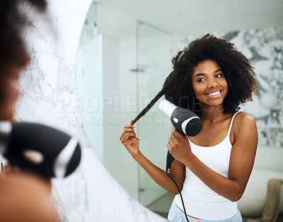 Buy stock photo Shot of an attractive young woman blowdrying her hair at home