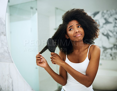 Buy stock photo Shot of an attractive young woman struggling to comb her hair at home