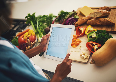 Buy stock photo Shot of an unrecognizable person holding a digital tablet over a bunch of vegetables in the kitchen at home