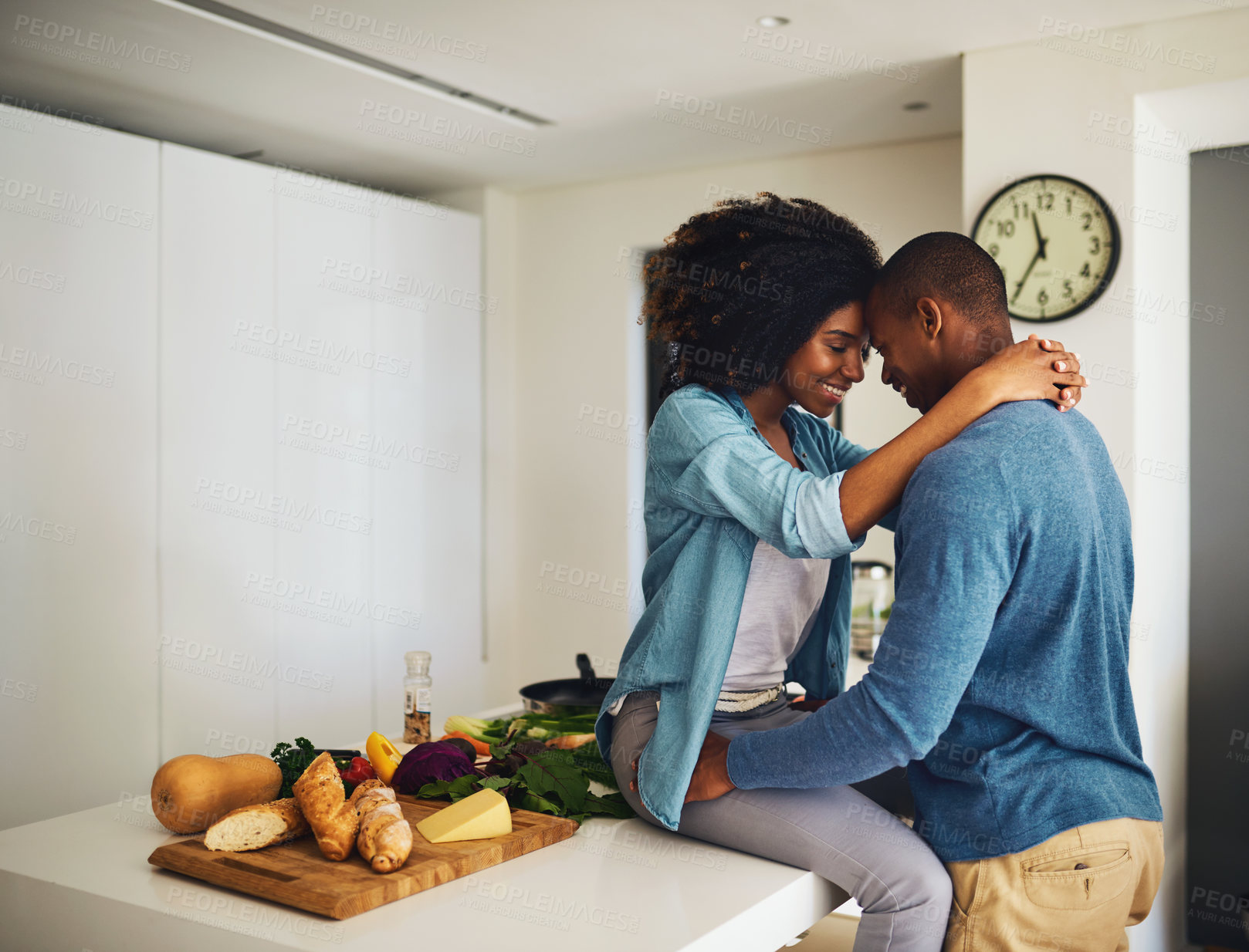 Buy stock photo Shot of a cheerful young couple holding each other and sharing a tender moment in the kitchen at home during the day