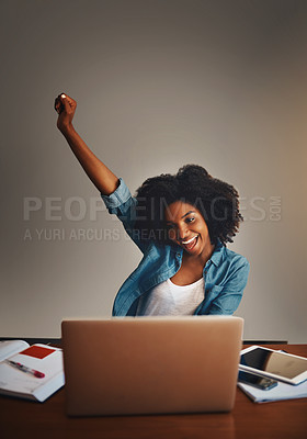 Buy stock photo Studio shot of an attractive young woman cheering while working on a laptop against a dark background