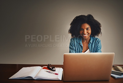 Buy stock photo Studio portrait of an attractive young woman working on a laptop against a dark background