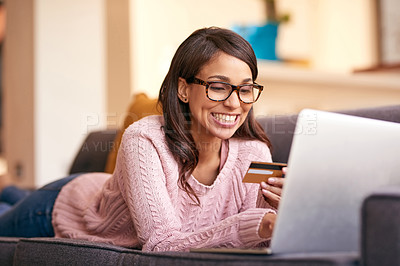 Buy stock photo Shot of an attractive young woman using a laptop and credit card on the sofa at home