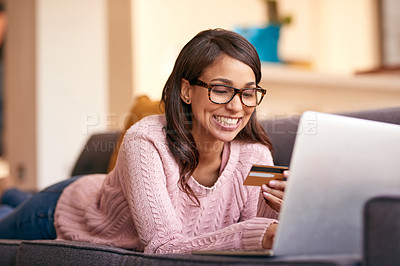 Buy stock photo Shot of an attractive young woman using a laptop and credit card on the sofa at home