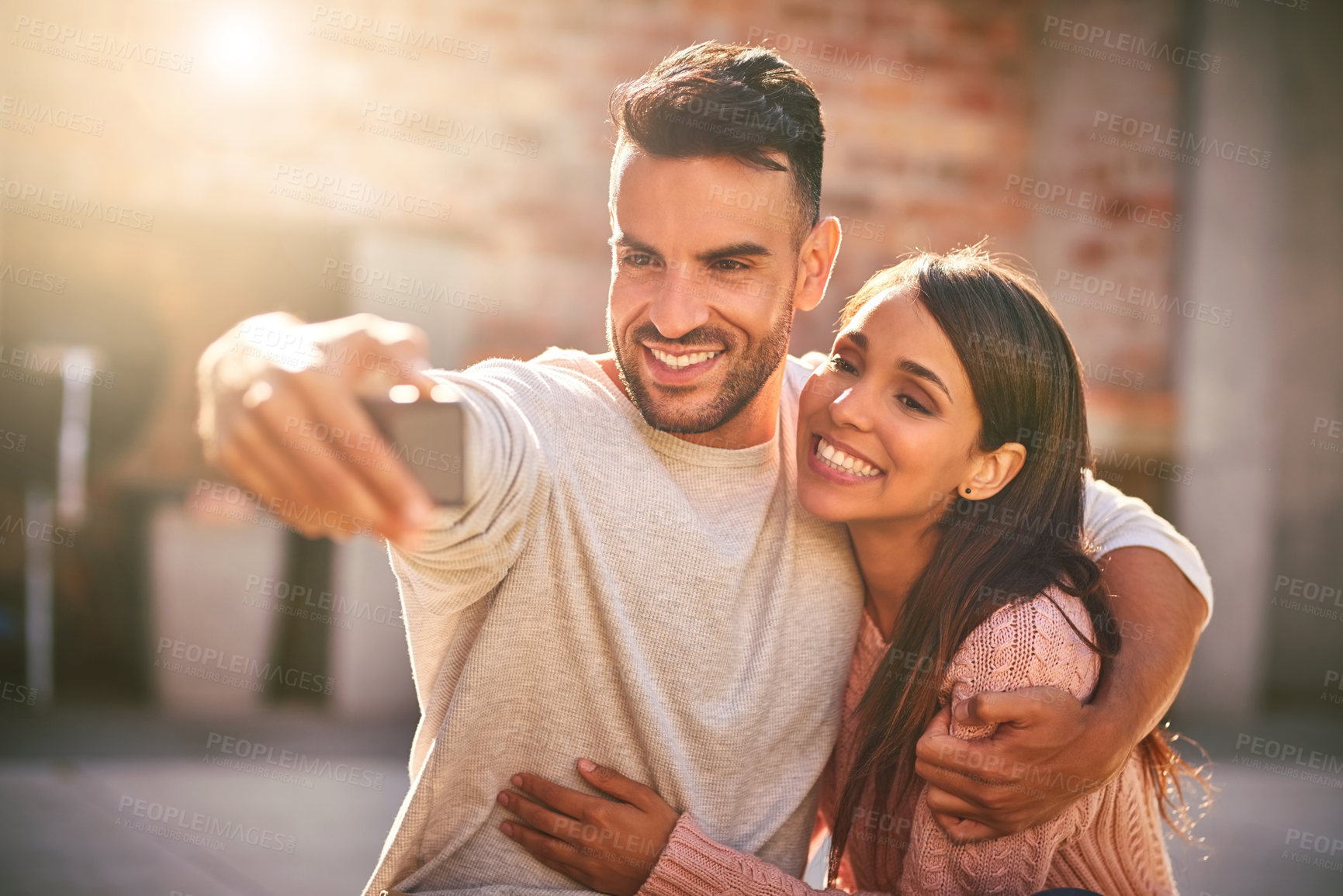 Buy stock photo Shot of a happy young couple taking selfies together outdoors