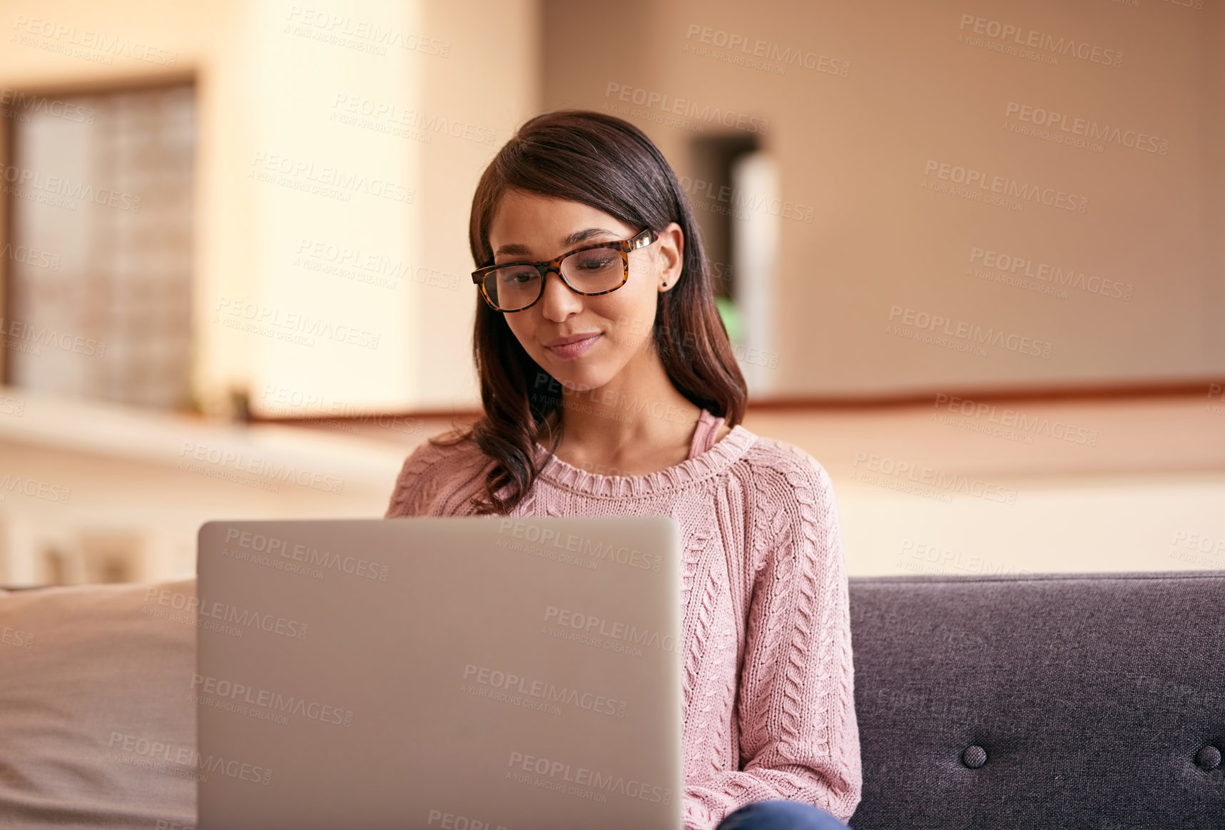 Buy stock photo Shot of an attractive young woman using a laptop on the sofa at home
