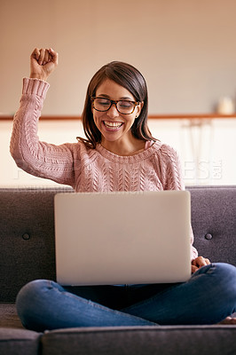 Buy stock photo Shot of an attractive young woman using a laptop on the sofa at home and cheering
