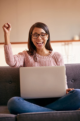 Buy stock photo Shot of an attractive young woman using a laptop on the sofa at home and cheering