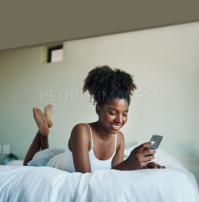 Buy stock photo Shot of a young beautiful woman using a cellphone in her bedroom at home
