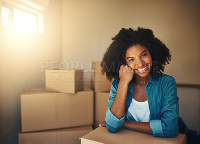 Buy stock photo Portrait of a cheerful young woman resting on her hand while being surrounded by cardboard boxes on moving day inside at home