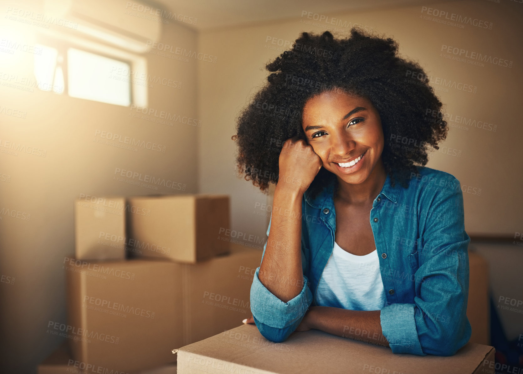 Buy stock photo Portrait of a cheerful young woman resting on her hand while being surrounded by cardboard boxes on moving day inside at home