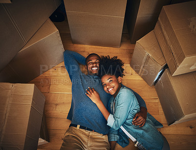 Buy stock photo Portrait of a cheerful young couple lying on the floor while being surrounded by cardboard boxes on moving day inside at home
