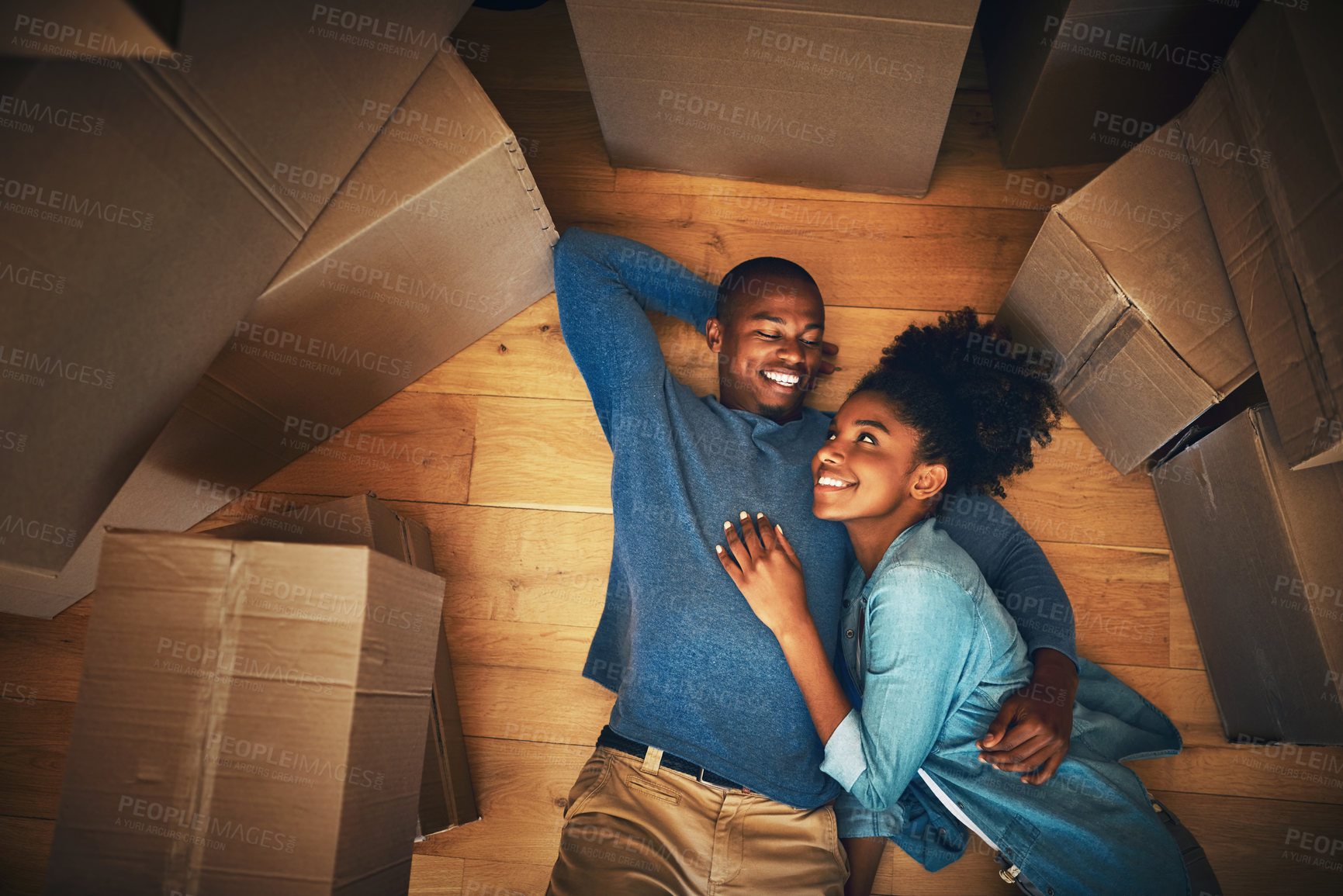 Buy stock photo Couple, boxes and lying on floor in new home for moving, real estate or property investment in living room. Above, black man and young woman with cardboard for hug, mortgage or relocation in house